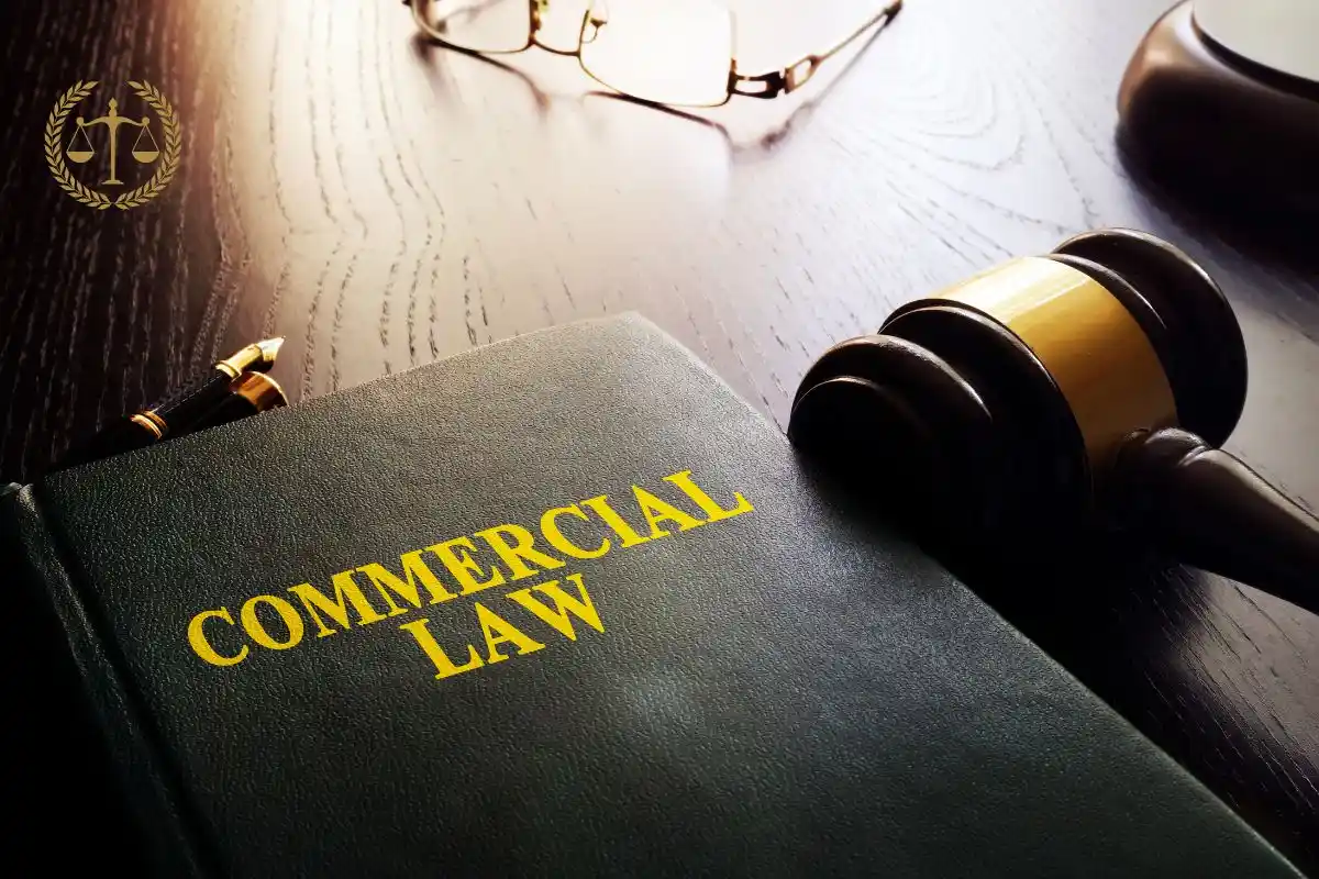 A book with 'commercial law' written on it with a gavel and a cartoon set of scales.